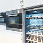 Elegant modern kitchen featuring built-in ovens and a wine cooler with stylish cabinetry.