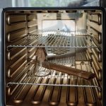 Glass flask placed inside an open industrial laboratory oven.
