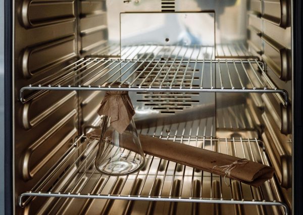 Glass flask placed inside an open industrial laboratory oven.